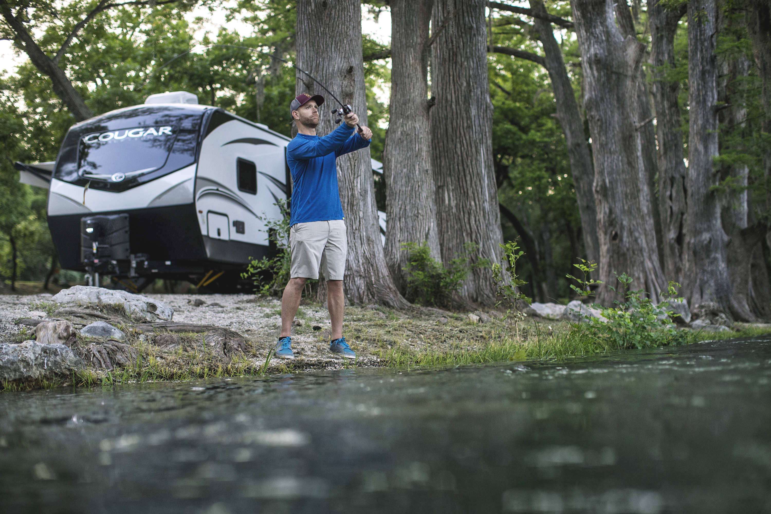Robert Field fishes in a lake with his Keystone Cougar parked behind him.